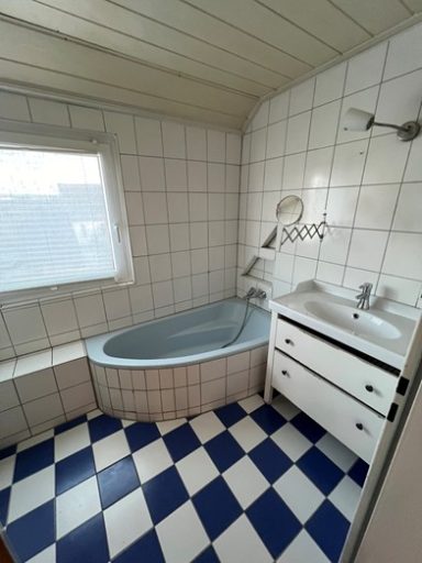 Helles Badezimmer mit Badewanne, Waschbecken und gefliester Fußboden in Schwarz und Weiß.