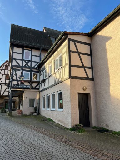 Fachwerkhaus mit modernen Elementen, gepflasterter Weg und blauem Himmel.