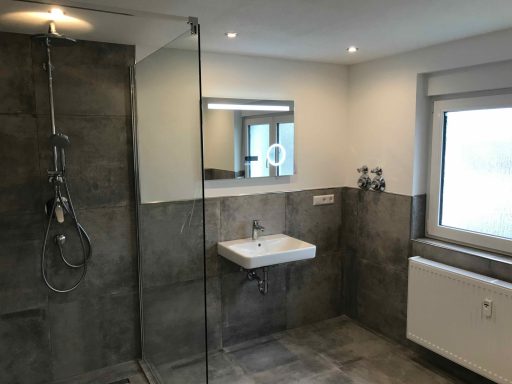 Modernes Badezimmer mit Dusche, Waschbecken und großer Fensterfront.