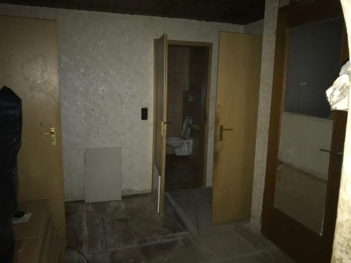 Dunkler Flur mit offener Tür zu einem Badezimmer und zwei Wandschränken.