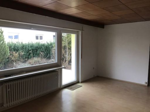 Heller Raum mit Fenster, moderne Heizung und Zugang zur Terrasse.