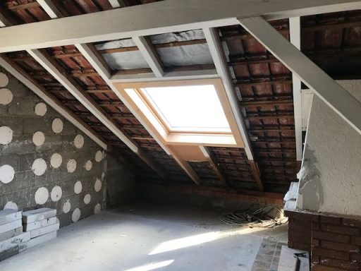 Dachboden mit unvollendeten Wänden und einem Dachfenster in der Mitte.